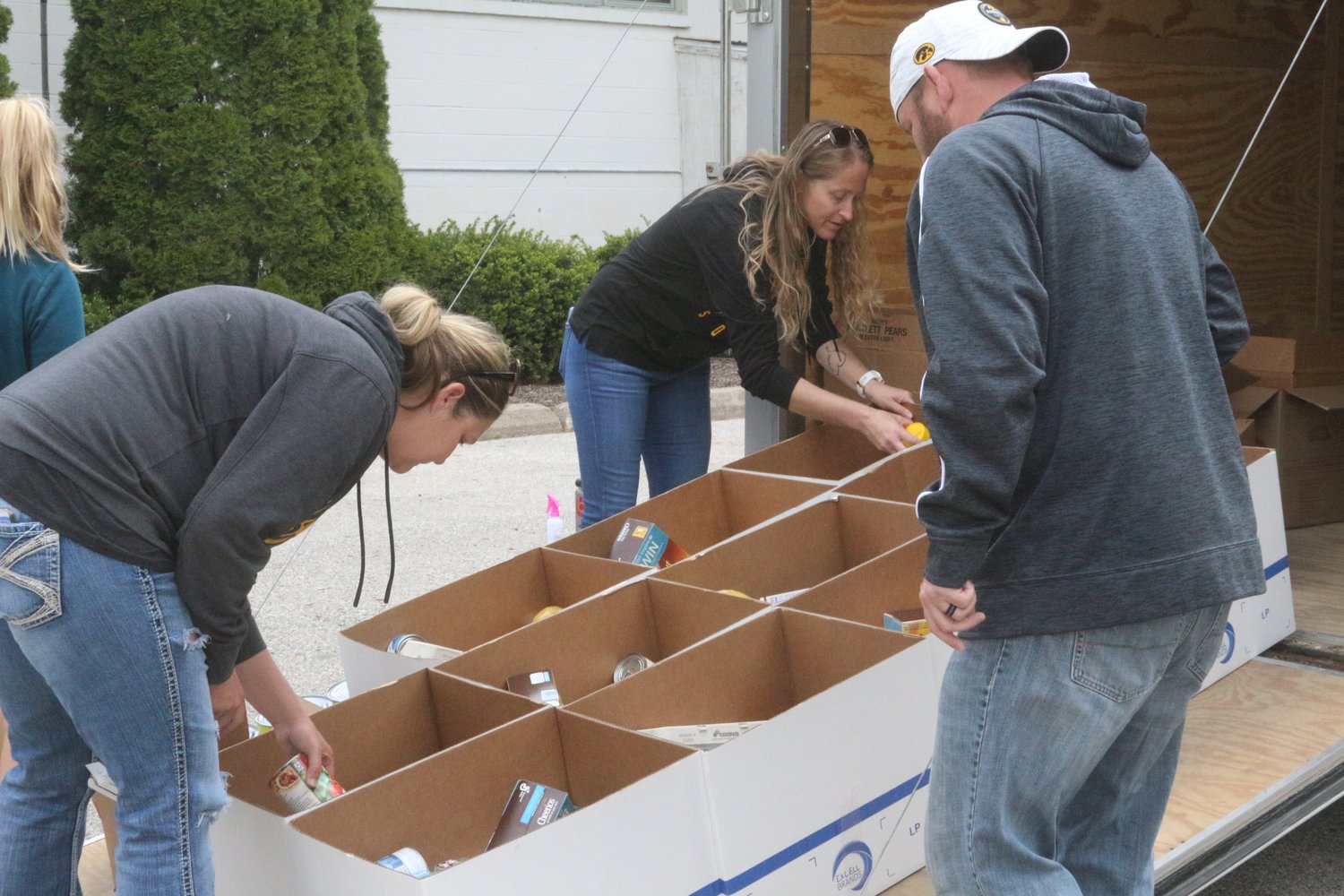 Wellman City Administrator Kelly Litwiller (left), City Clerk Beth VanWinkle (center) and City Council Member Shannon McCain place food in boxes.
